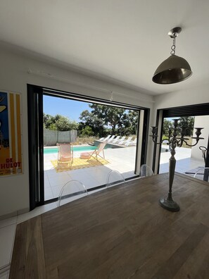 Un interior moderno con un amplio ventanal corredera que da a una zona de piscina exterior.