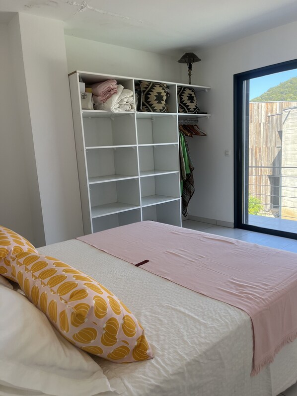 Un dormitorio con cama, armario y ventana con vista a un edificio.