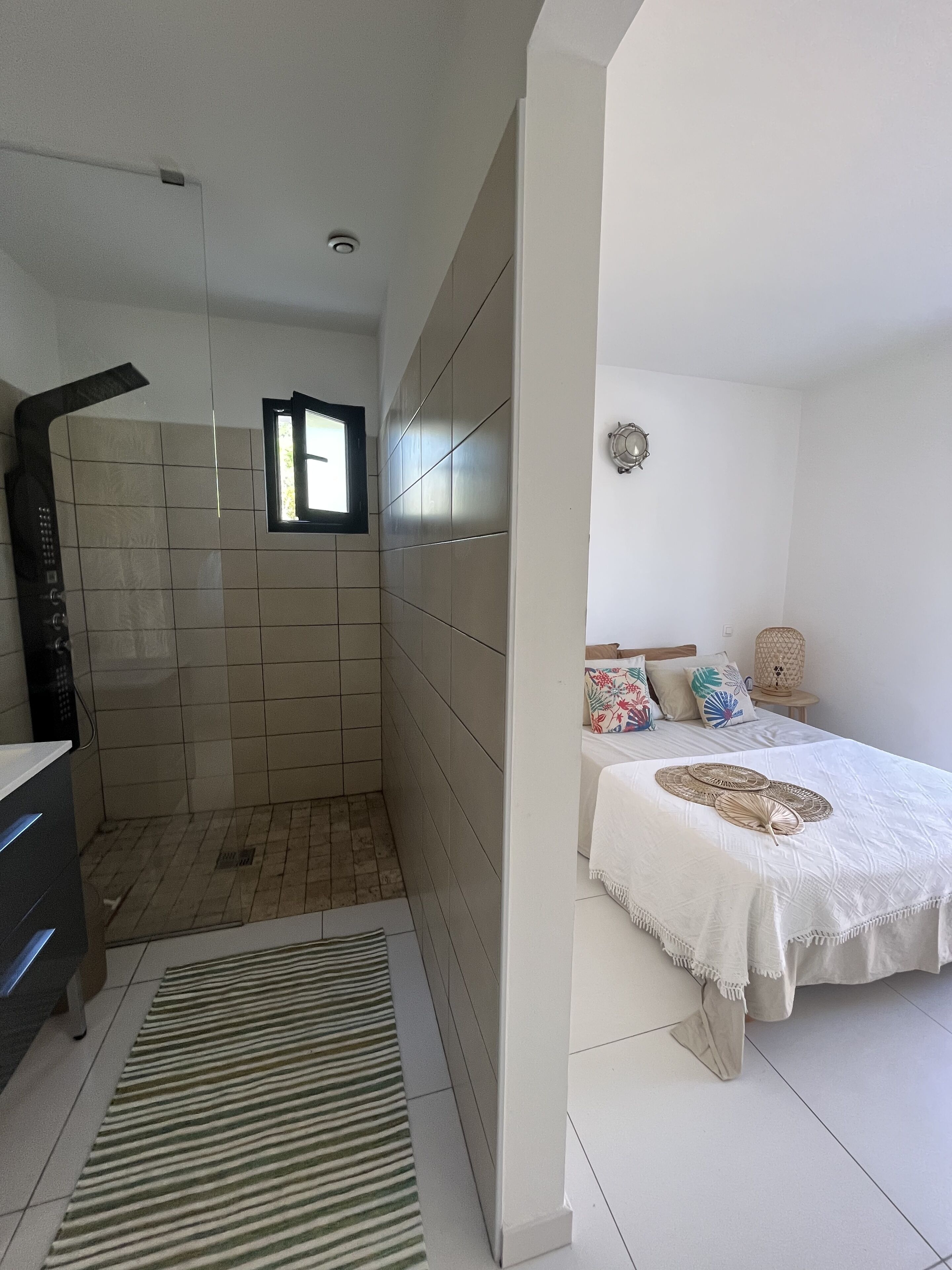 A bathroom with a shower, a toilet, and a sink. There is a window providing natural light.