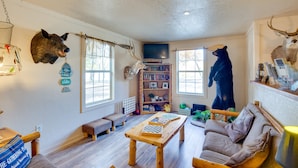 Een gezellige woonkamer met een houten tafel, een bank en een beerbeeld.