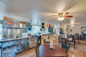 A restaurant interior with a counter, tables, chairs, ceiling fans, and various signs. - Community Pier: Cozy Kerens Cabin! (Kerens)