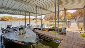 A covered boat dock with several boats moored, a dockside chair, and a water filtration system.