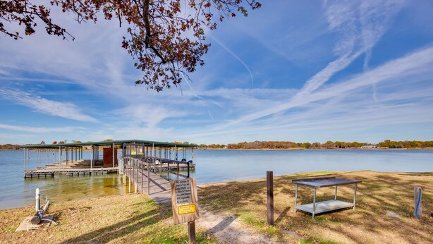 A lakeside pier with a covered seating area, a dock, and a picnic table.