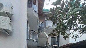 A modern building with a spiral staircase, a potted plant, and a concrete floor. - Tekirova Dora Butik Otel  (Kemer)