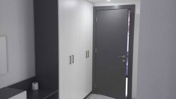 Una stanza moderna e minimalista con un armadio scuro, una piccola scrivania e una porta che dà su un'altra area.