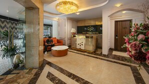 A hotel lobby with a reception desk, a chandelier, a seating area, and a potted plant. - BAO NGOC HOTEL LINH DAM (Hanoi)