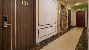 A hallway with a wooden door labeled "101" and an elevator. - BAO NGOC HOTEL LINH DAM (Hanoi)