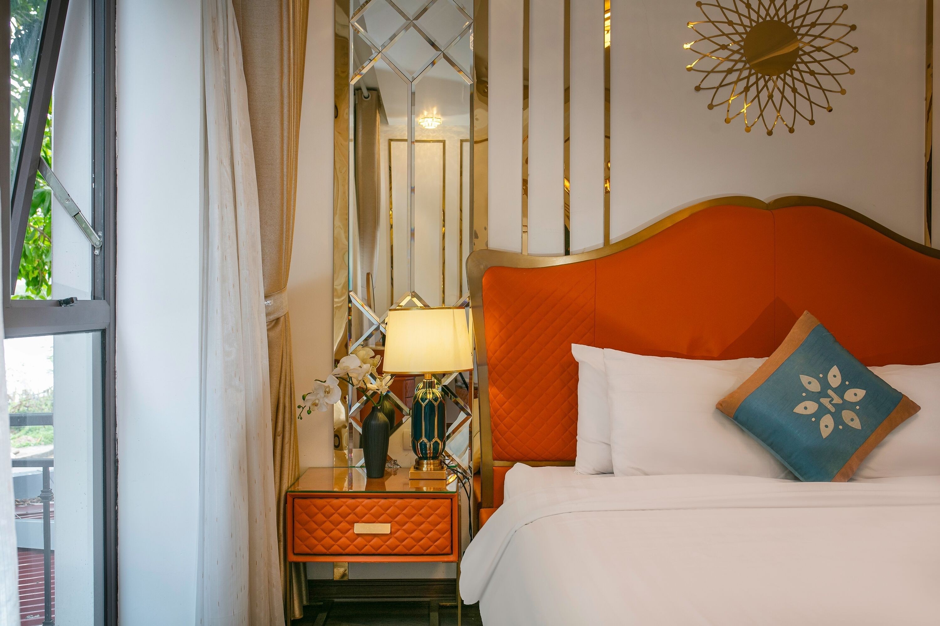 A hotel room with a bed, a nightstand, a lamp, and a mirror.