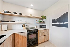 Une cuisine moderne dotée d’une cuisinière intégrée, d’un four à micro-ondes et d’armoires en bois.