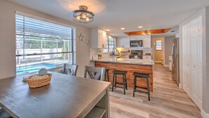 A modern kitchen with a central island, wooden flooring, and large windows. - Nautical Nook Pool Home (Brandon)
