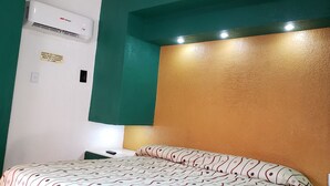 Una habitación con cama, aire acondicionado y una lámpara fijada a la pared.