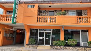 Un hotel con una estructura de dos pisos, balcones con barandillas y un letrero que indica que es un hotel.