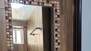 Un baño con tocador de madera, un lavabo blanco y un espejo con marco decorativo.
