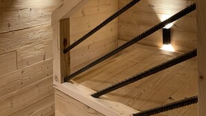 Una escalera de madera con barandilla e iluminación empotrada en la pared.