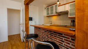 Cocina compacta con encimera de madera, salpicadero de ladrillo y armarios blancos.