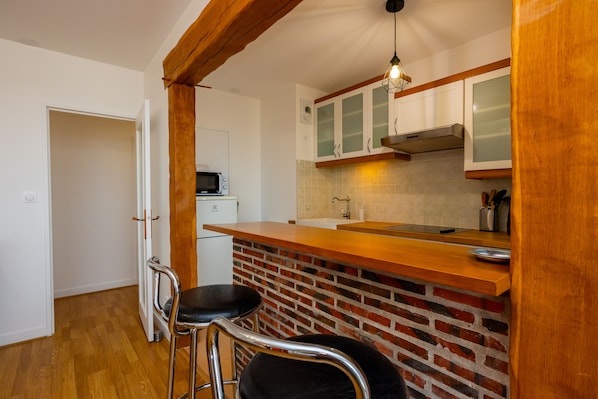 Une cuisine de taille réduite avec un plan de travail en bois, un mur recouvert de briques et des armoires blanches.