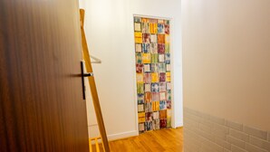 Un pasillo con piso de madera, una pared blanca y una obra de arte abstracta y colorida en la pared contigua.