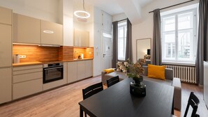 A modern kitchen with wooden countertops, a dining area with a black table, and a living space with a sofa and a radiator. - Eclectic and Design Duplex in the Heart of Prague by EasyBNB Premium (Prague)