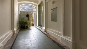 A hallway with a tiled floor, white walls, and a door at the end. - Eclectic and Design Duplex in the Heart of Prague by EasyBNB Premium (Prague)
