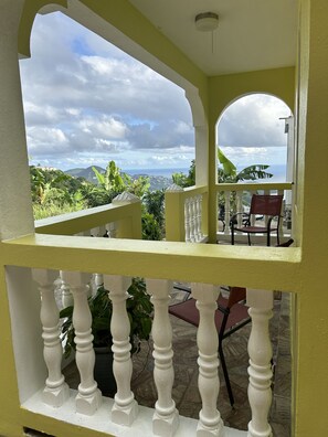 A balcony with a view of mountains and the sea, white balustrades, and outdoor seating. - Zoë Oasis - The Couple’s Choice & #1 Wholesome Getaway 🤍 (St Thomas)