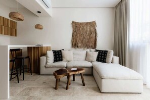 Ein modernes Wohnzimmer mit einem Ecksofa, einem kleinen Holztisch und einer Wandweberei.