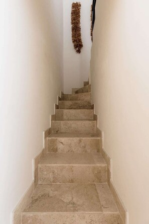 Eine Treppe mit beigen Stufen und weißen Wänden, die zu einer höheren Etage führt.