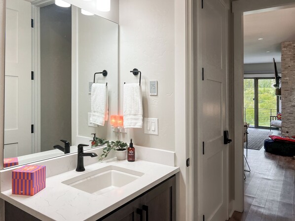- Freshen up in this sleek bathroom with clean finishes and bright light - Black fixtures and white countertop add contrast and elegance - Hand towels, soaps, and decor ensure a welcoming guest touch