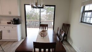 Un coin repas avec une table en bois, des chaises et une vue sur une terrasse extérieure, accessible par une porte vitrée.
