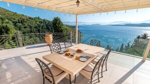 A terrace with a table set for breakfast, overlooking a scenic view of a lake and mountains. - Kalami Beach - Villa Kouloura (Corfu)