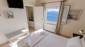 A hotel room with a bed, a bench, a window with a view of the sea, a mirror, and a painting on the wall. - Kalami Beach - Villa Kouloura (Corfu)