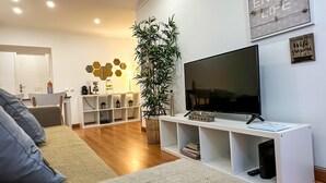 A modern living room with a flat-screen TV, a white console table, and a large potted plant.