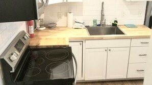 Una cocina con estufa, pileta y armarios blancos.