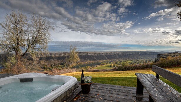 A hot tub on a wooden deck with a scenic view of a valley and mountains. - Canyonside Retreat - Park-like setting, Panoramic Views with Hot tub & Firepit!! (Buhl)