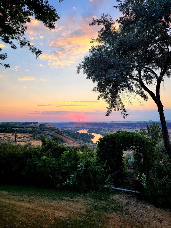 A landscape view with a sunset, hills, and a river.