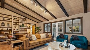 A spacious living room with a wooden ceiling, a large sofa, two armchairs, a coffee table, and a bookshelf filled with decorative items. - Ritz-Craterton|Spa + BBQ + Game Room + EV + Pups (Big Bear Lake)