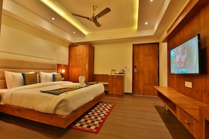 Quarto moderno com uma cama grande, guarda-roupa de madeira, televisão e ventoinha no teto.