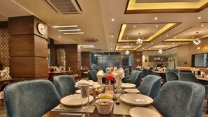 A restaurant with multiple dining tables set with plates, glasses, and napkins. - HOLY VIVASA  (Rishikesh)
