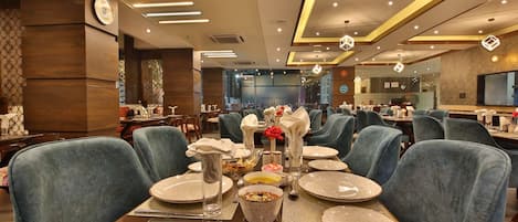 A restaurant with multiple dining tables set with plates, glasses, and napkins.