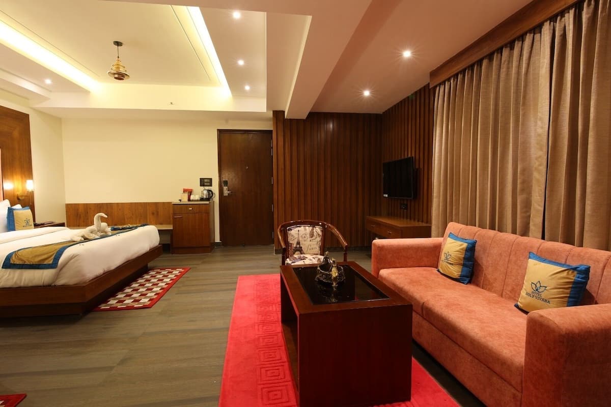 A hotel room with a bed, a sofa, a coffee table, a desk, and a television.