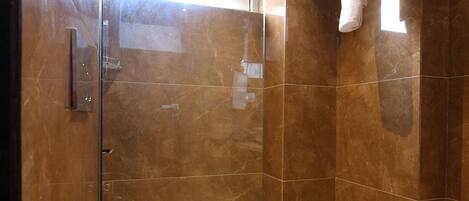 A modern bathroom with a glass-enclosed shower, a white toilet, and a towel rack.