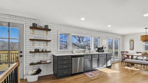 A modern kitchen with white subway tiles, stainless steel appliances, and wooden shelves.