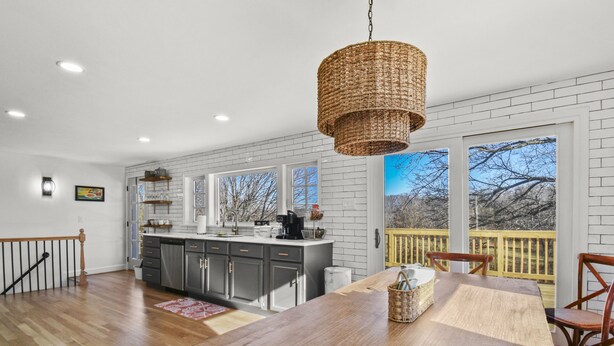 A spacious kitchen with a large island, white brick walls, and a wooden deck with a railing.