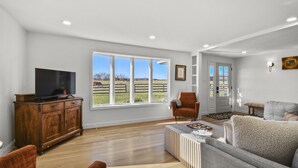 A spacious living room with a large window, wooden furniture, and a television.
