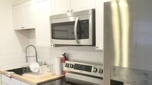 Eine moderne Küche mit Edelstahlgeräten, darunter Mikrowelle, Backofen und Kühlschrank.