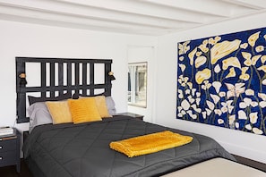 A bedroom with a bed, a nightstand, a lamp, and a large abstract painting on the wall.