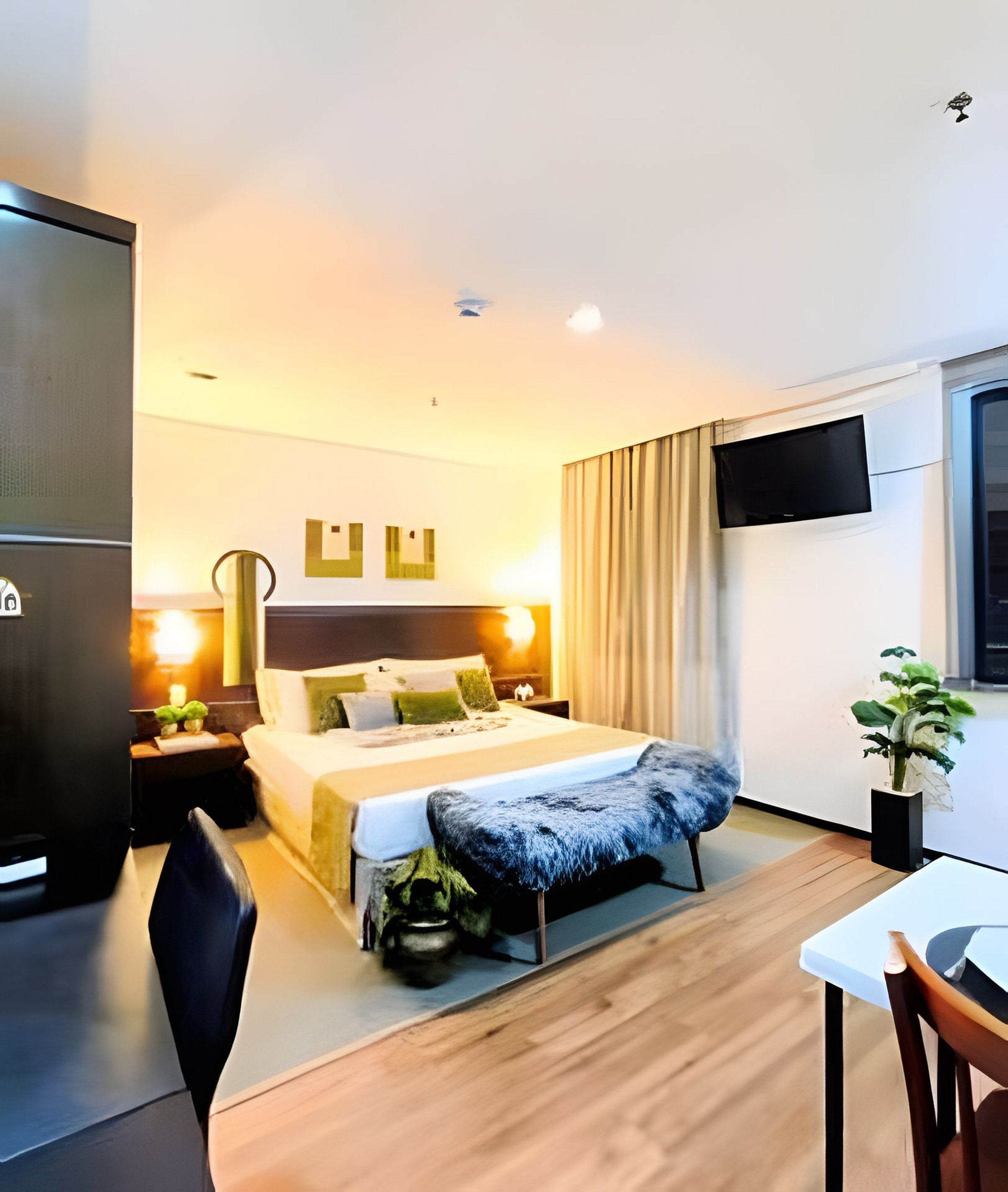 Une chambre d’hôtel comprenant un lit, des tables de chevet, un téléviseur, un bureau et une chaise.