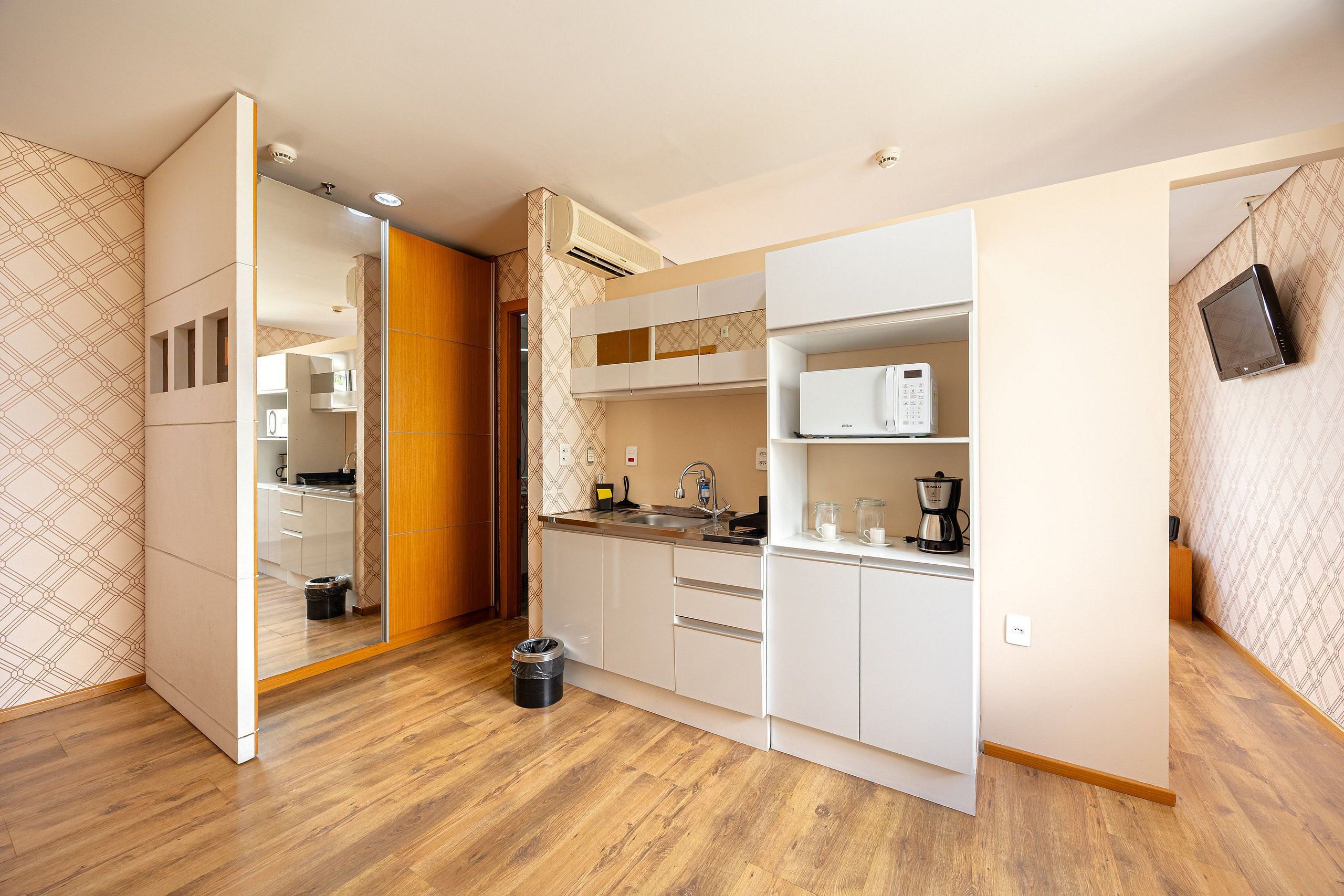 A compact kitchen with white cabinets, a microwave, and a sink.