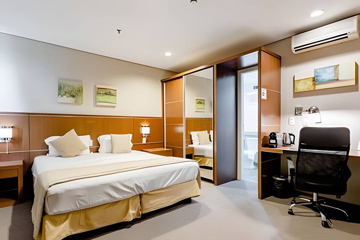 Ein Hotelzimmer mit Bett, Schreibtisch, Stuhl und Klimaanlage.