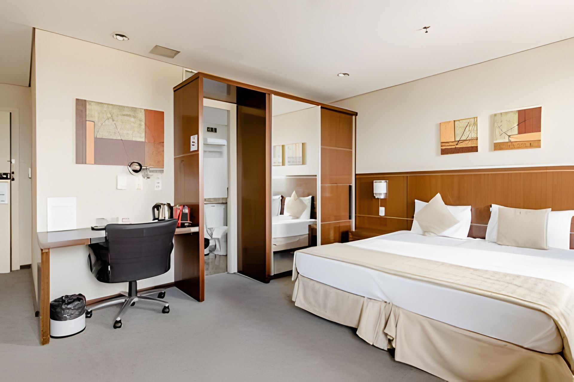 Una habitación de hotel con cama, escritorio, silla y vestidor.