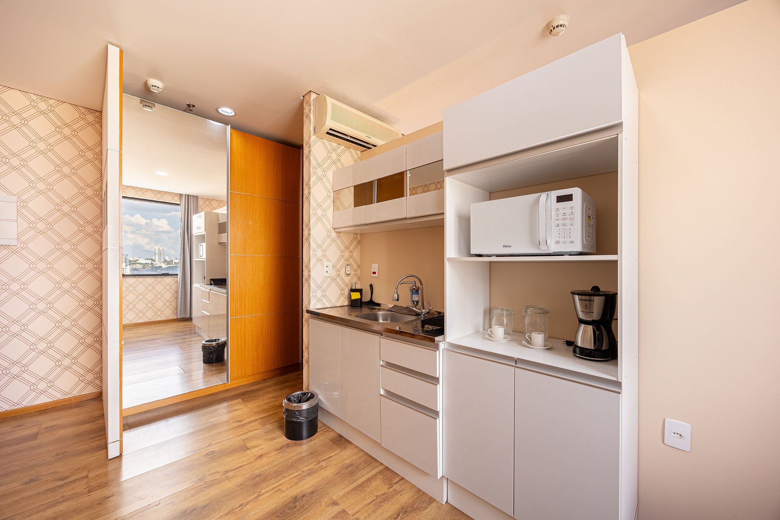A modern kitchen with white cabinetry, a built-in microwave, and a coffee maker.